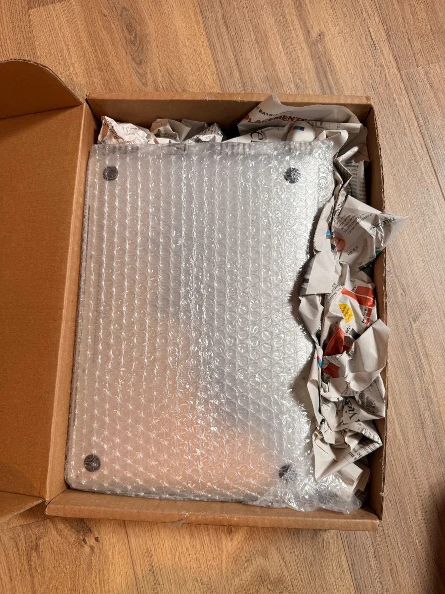 Un MacBook emballé dans du film à bulles, calé dans un carton
