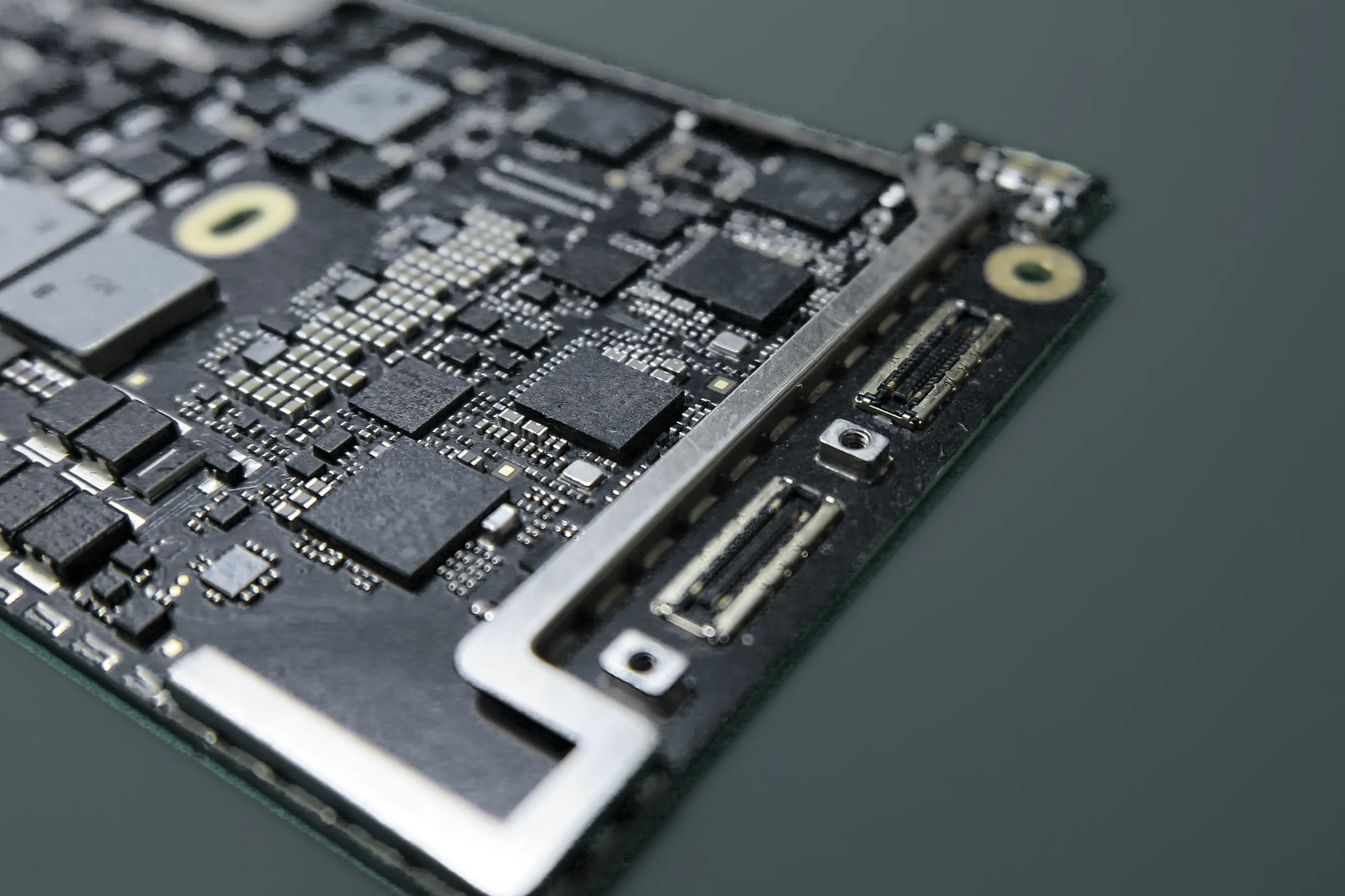 Gros plan sur une carte mère de MacBook : ses composants, son cadre métallique et ses connecteurs
