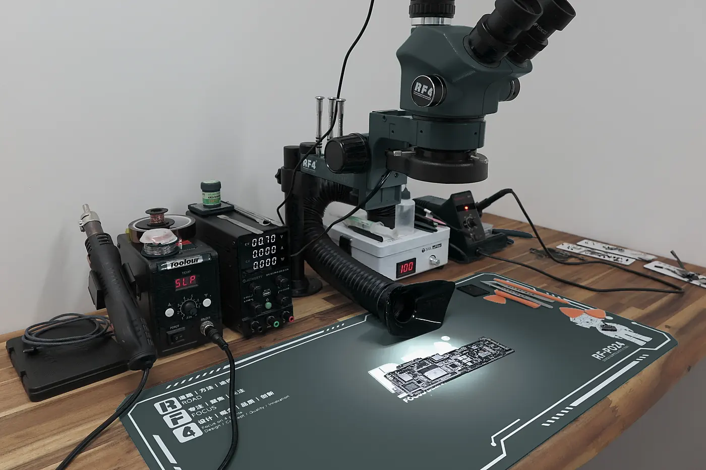 L’établi : microscope binoculaire, alimentation de laboratoire et station de soudure, une carte sous la lumière
